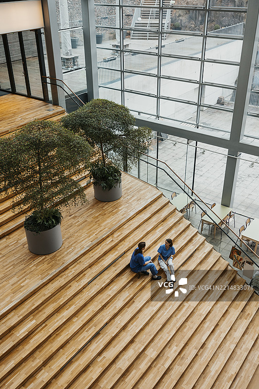 高角度视角下的女性医学专家在医院楼梯上交谈图片素材