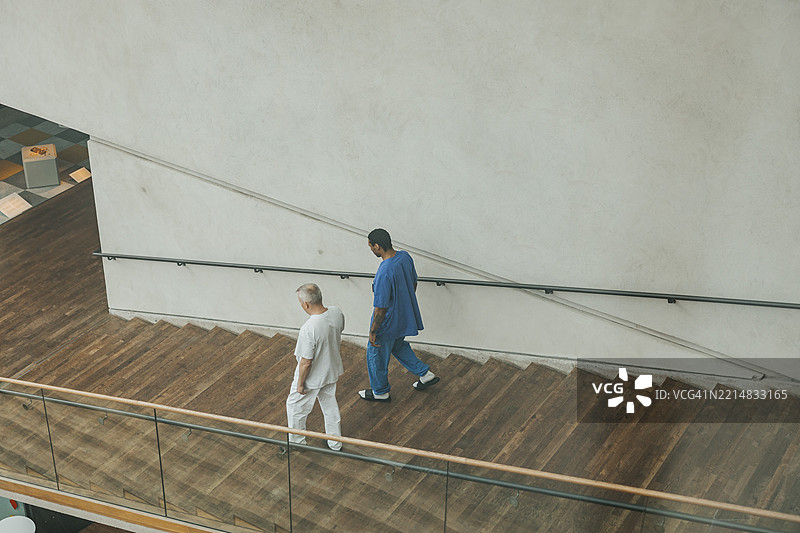 男性医生穿着医疗制服从医院楼梯上走下的高角度视图图片素材