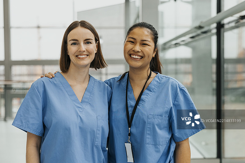 微笑的女护士在医院与同事亲密合影图片素材