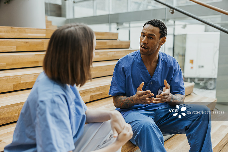 男医生与女护士坐在医院楼梯上讨论图片素材