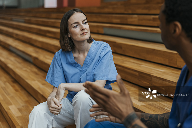 女护士坐在医院楼梯上倾听同事的讲话图片素材