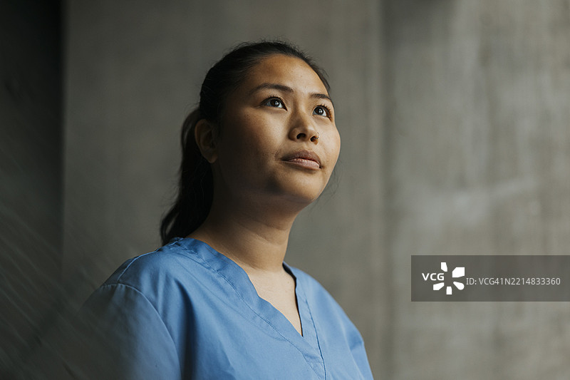 深思的年轻女性医护工作者望向远方图片素材