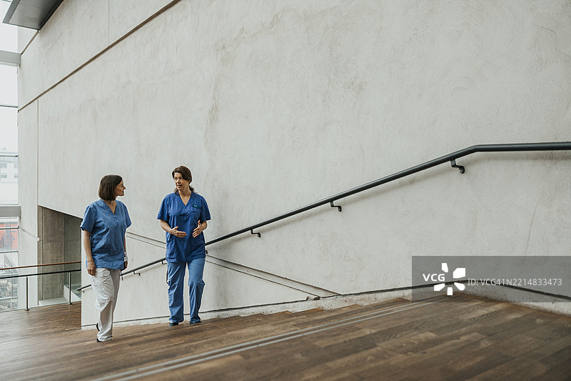 穿着医用工作服的女性医生在医院楼梯上走动图片素材