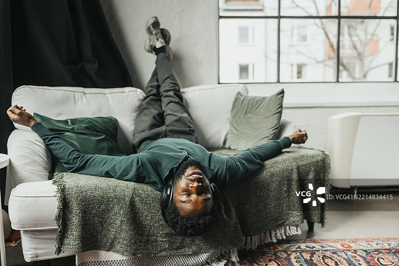 无忧无虑的商人在办公室沙发上躺着，脚抬起，听着音乐图片素材