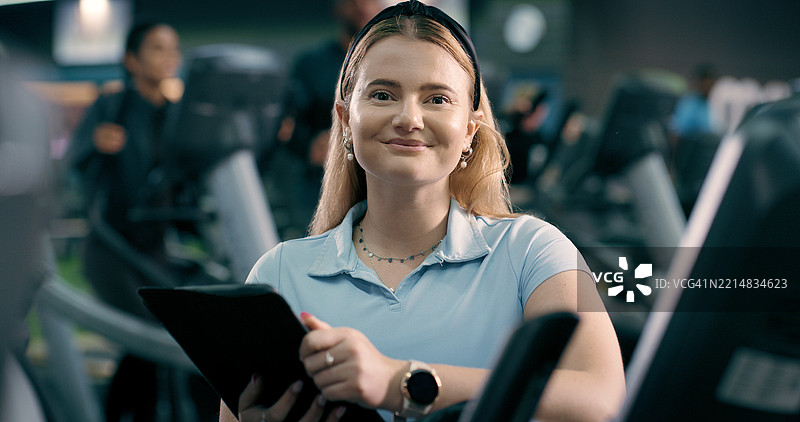 快乐的女性，健身房内的个人教练肖像，手持平板电脑用于注册或健身会员。积极的女性或协调员面带微笑，使用科技或健康服务，欢迎加入健身俱乐部。图片素材