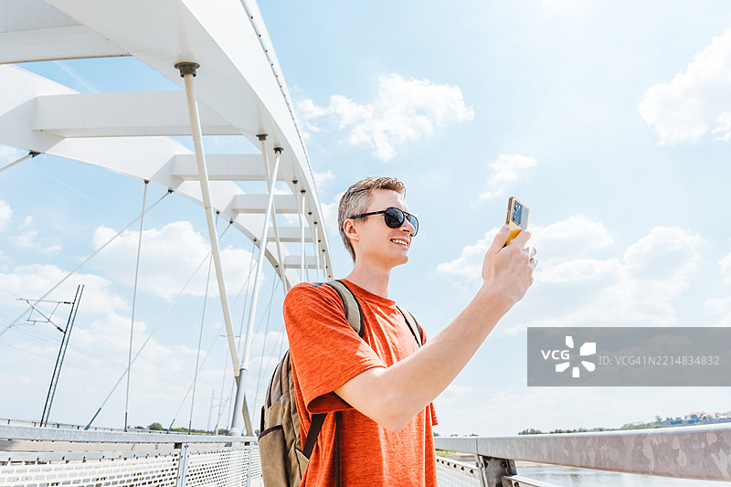 戴着太阳镜的男子在户外走路时打电话图片素材