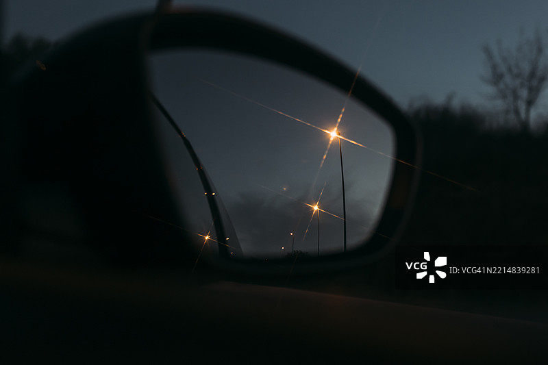 后视镜反射黄昏时的街灯，营造出一种阴暗而富有氛围的场景图片素材