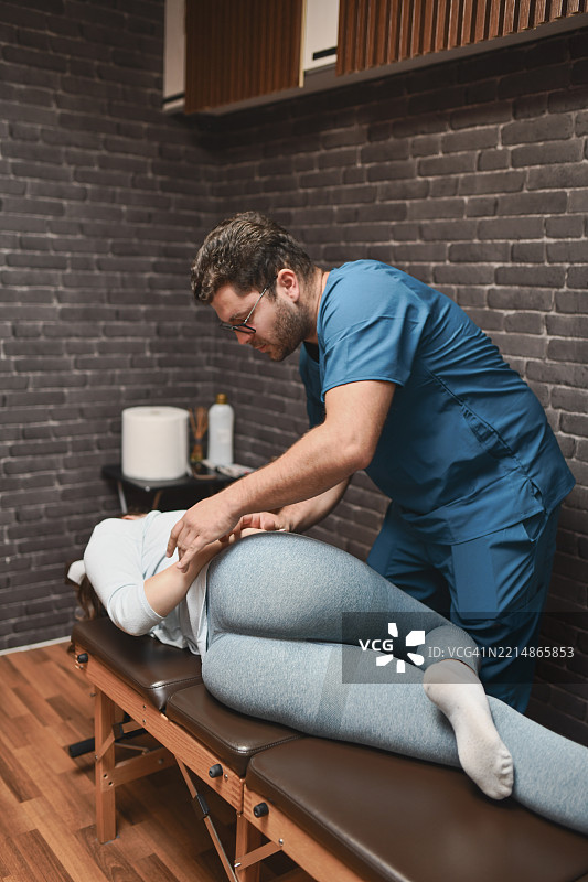 脊椎按摩师为侧卧女性患者进行脊柱调整定位图片素材