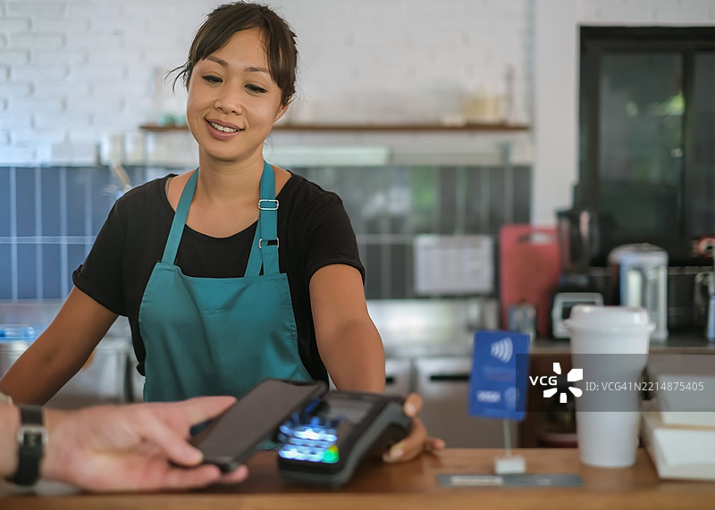 咖啡馆工作人员接受顾客的非接触式支付图片素材