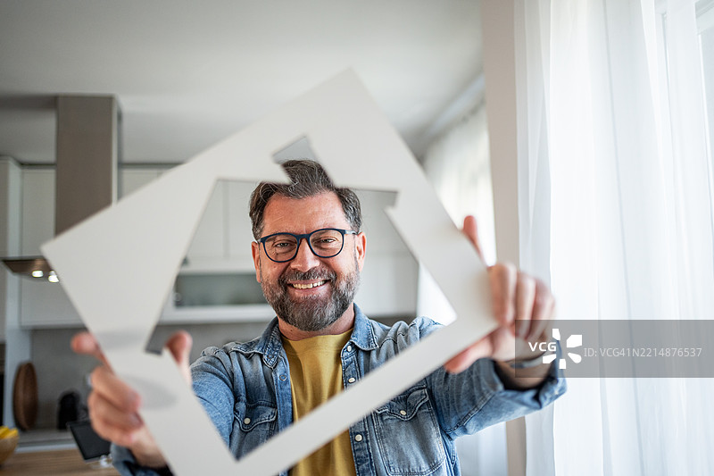微笑的建筑师手持房屋框架，象征着新家设计图片素材