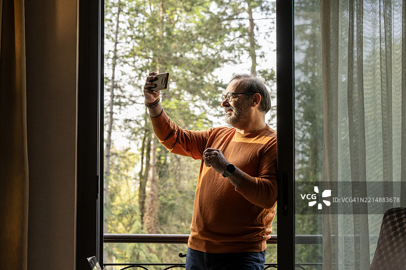 微笑的老年商人在办公室环境中使用智能手机图片素材