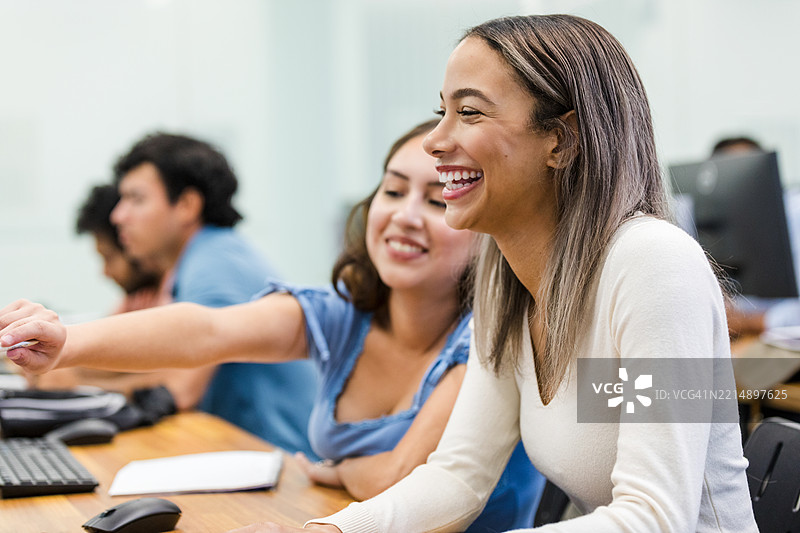 快乐的多元化学生在教室里合作使用笔记本电脑图片素材