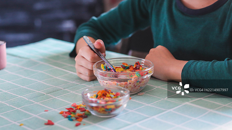 一个男孩在厨房的桌子上吃早晨的牛奶麦片早餐。图片素材