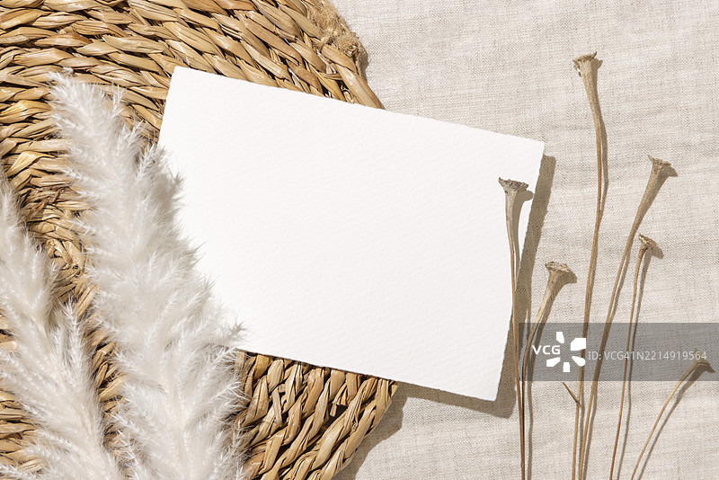 米色编织餐垫和亚麻布上的干草旁边的空白卡片，波西米亚风格的样板图片素材