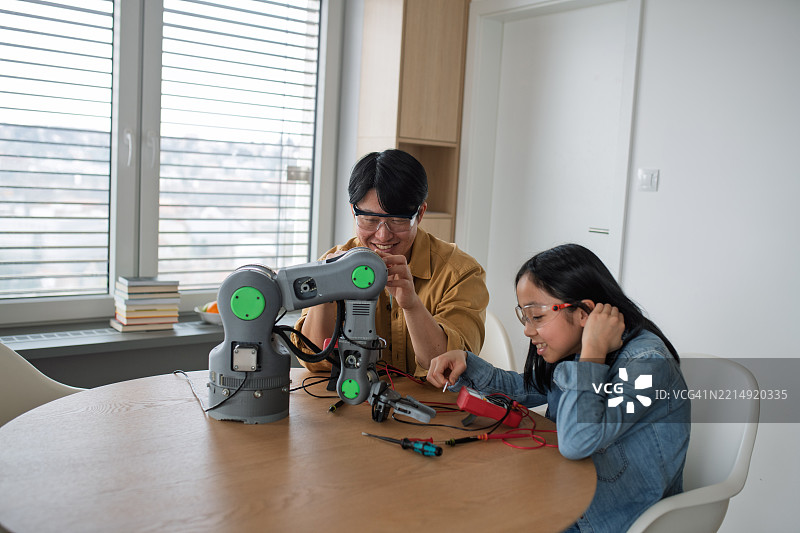 兄弟姐妹在家一起组装机器人套件。图片素材
