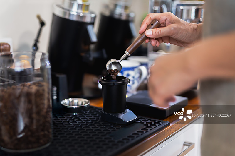 女咖啡师正在舀取烘焙好的咖啡豆以制作新鲜的浓缩咖啡图片素材