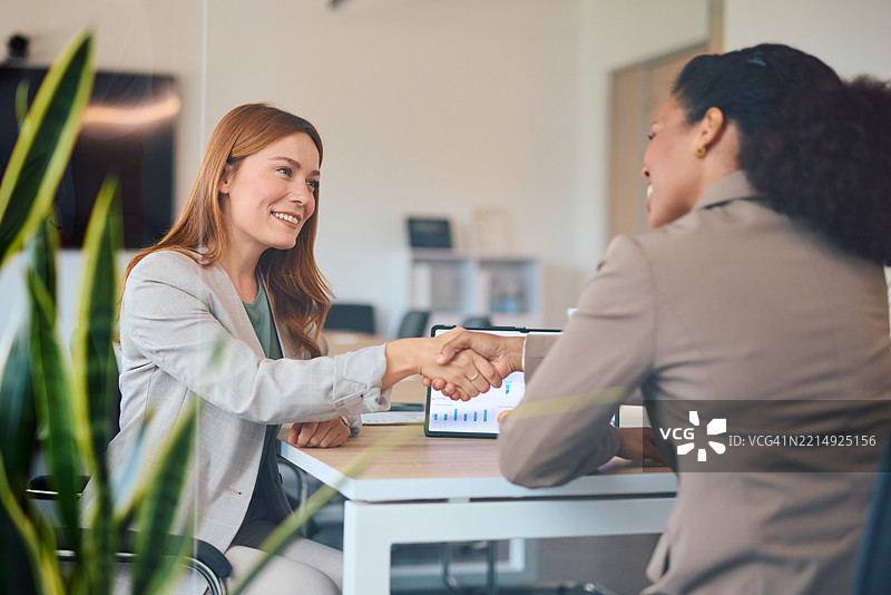 两位女商人在成功的商务会议后握手。图片素材