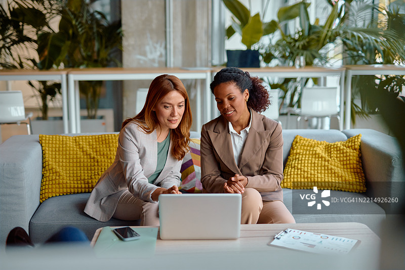 两位女商人在现代办公室里一起使用笔记本电脑工作图片素材
