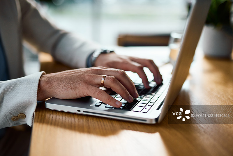 商人在现代办公室里使用笔记本电脑打字图片素材