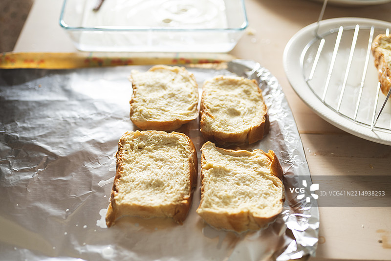 用布里欧修面包制作法式吐司，特写镜头展示浸泡在牛奶中的面包片，准备在锅中煎炸，制作甜味法式吐司。图片素材