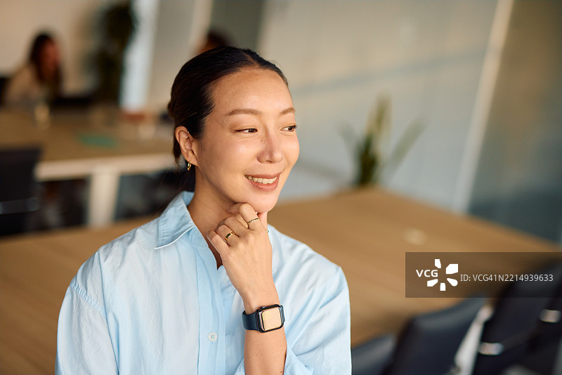 年轻的亚洲女商人在现代办公室微笑并思考图片素材