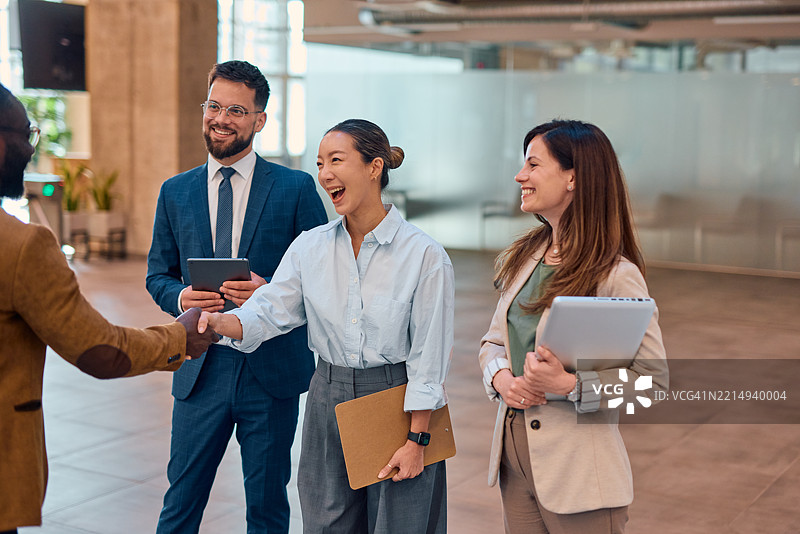 现代办公室大堂中商务人士握手交流图片素材