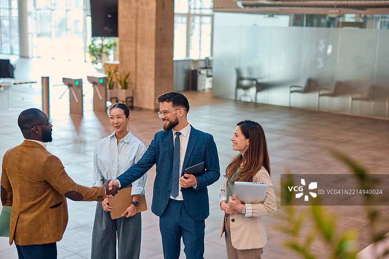 现代办公室大堂中商务人士握手交流图片素材