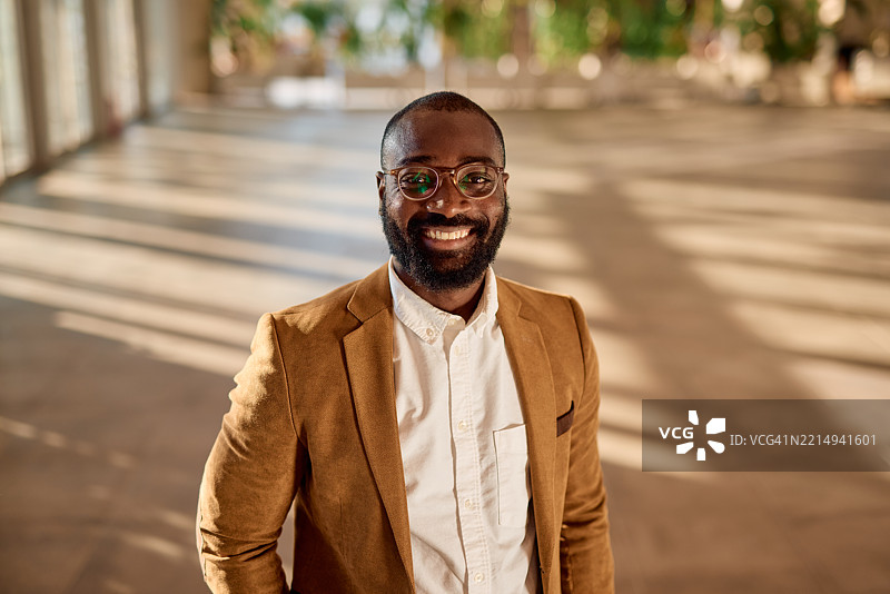 微笑的黑人商人在明亮的办公室空间中肖像图片素材