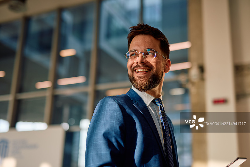 微笑的商人在现代办公大楼中向一旁看去图片素材