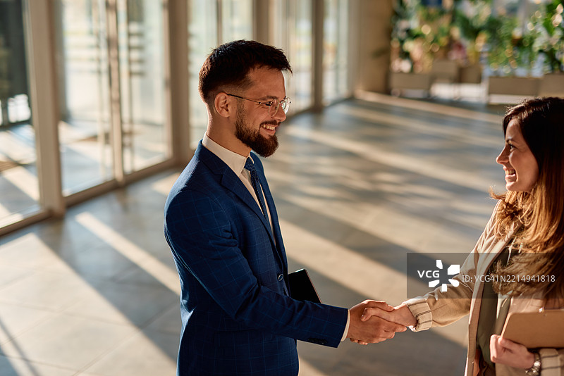 商人和女商人在现代办公大楼中握手图片素材