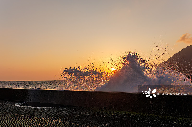 太平洋的汹涌波涛沐浴在八丈岛的晨光中。清晨时分，底港和底港海滩的日出。图片素材
