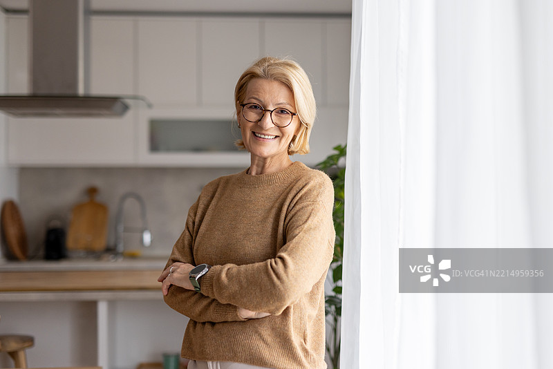 阳光明媚的厨房里，快乐的女性摆姿势。图片素材