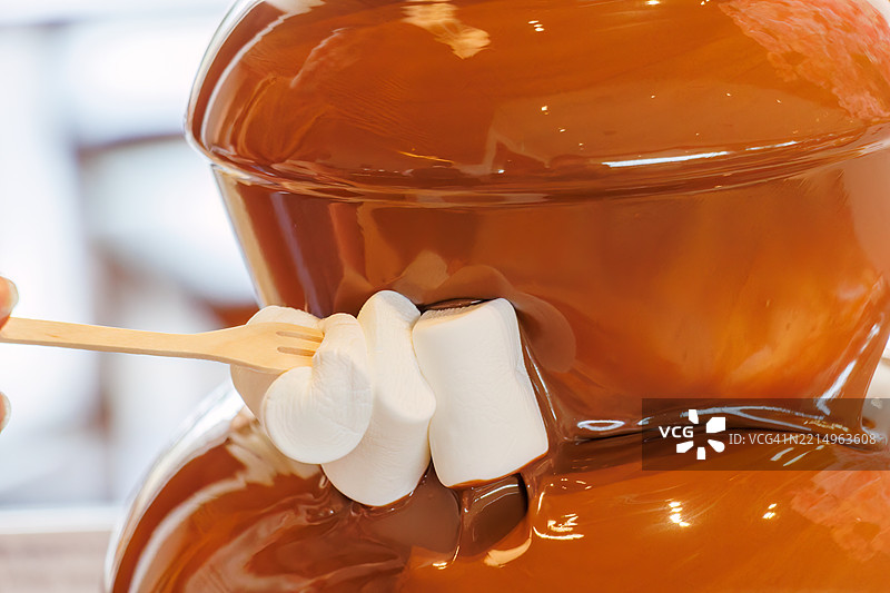 华丽的巧克力喷泉。自助餐厅。许多食物摆放在春天樱花的展示下。图片素材