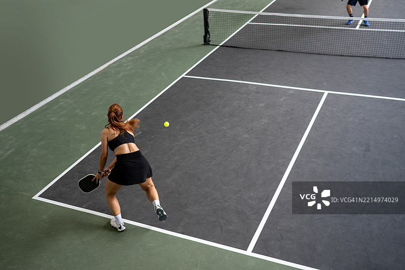 高角度视图的女性皮克球运动员击球瞬间图片素材