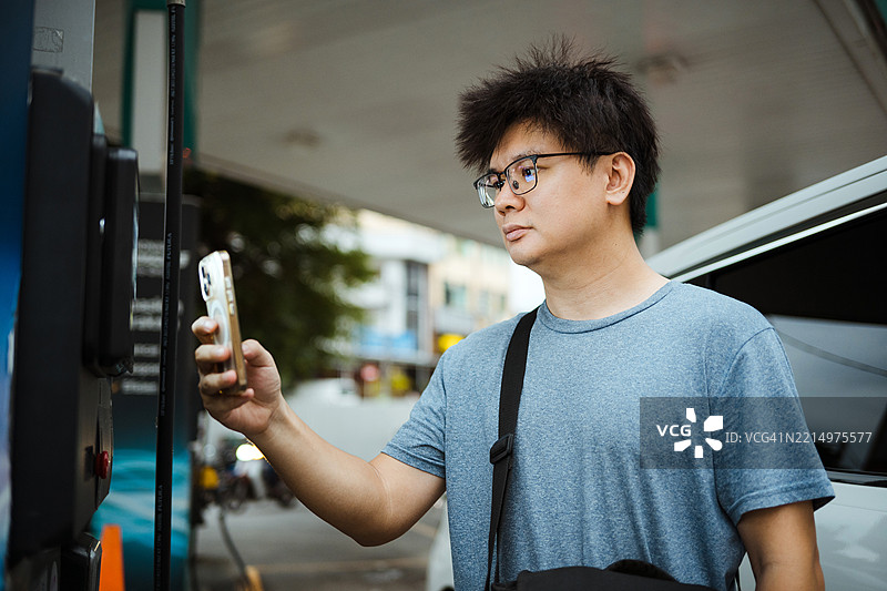 亚洲男子在自助加油泵使用ePal支付图片素材