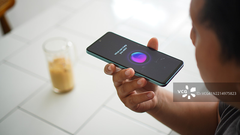 亚洲年轻男子使用智能手机语音助手的特写镜头图片素材