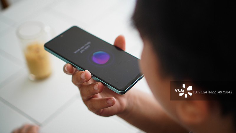 亚洲年轻男子使用智能手机语音助手的特写镜头图片素材