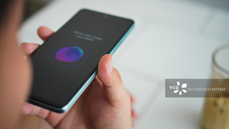 亚洲年轻男子使用智能手机语音助手的特写镜头图片素材