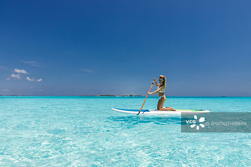 Happy woman enjoying in stand up paddle during summer day at sea.图片素材
