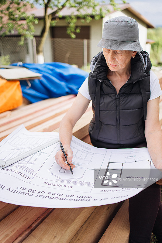 成熟的女性工程师在框架房屋施工现场查看蓝图图片素材