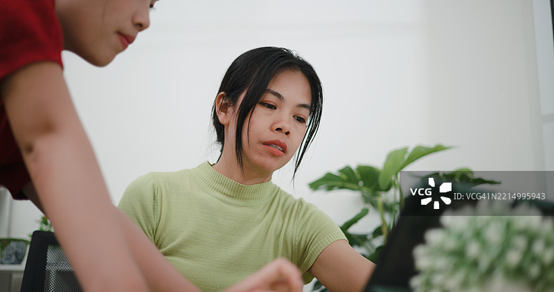 两位亚洲女性在家中的客厅桌子上一起规划财务。图片素材