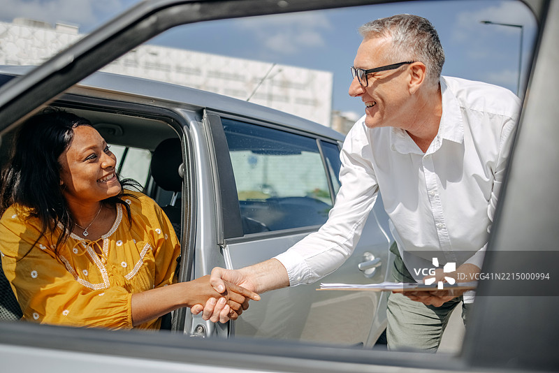 年轻女性与教练一起上驾驶课，顺利通过驾驶考试后收到祝贺图片素材