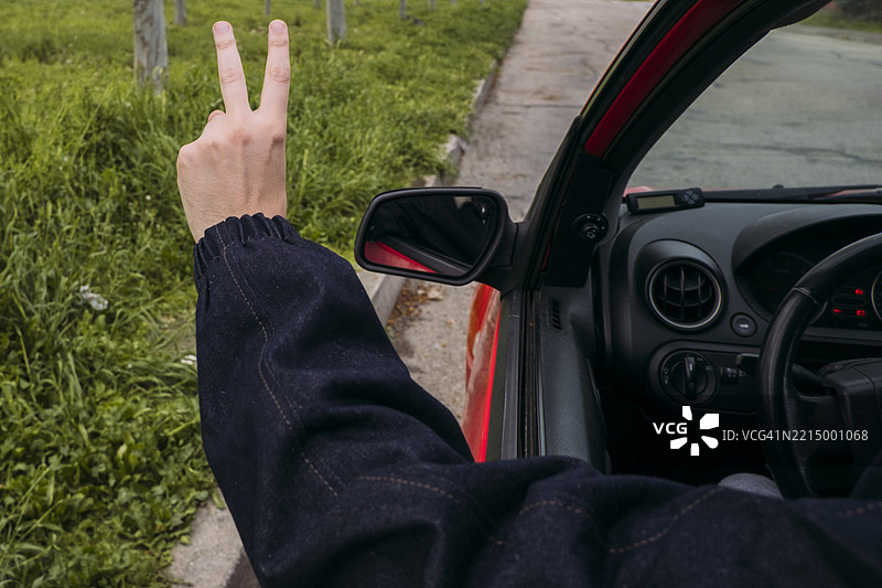 年轻男子在旅行时从车窗外做出胜利手势图片素材