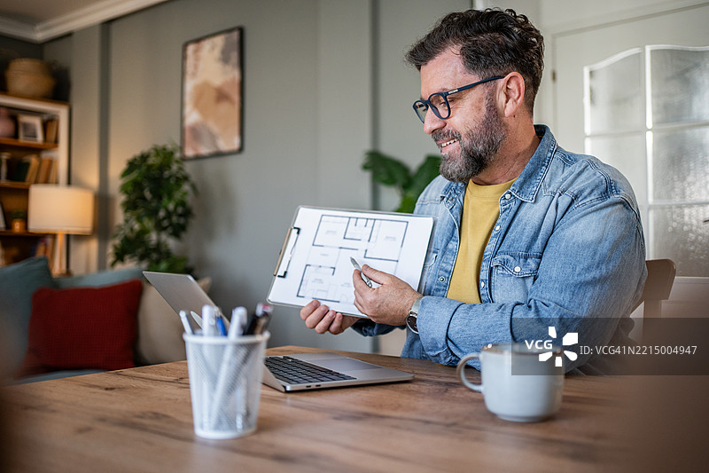 建筑师在家办公室通过视频通话展示蓝图图片素材