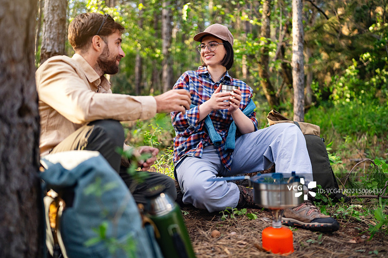 一对年轻情侣在宁静的森林环境中享受露营。图片素材