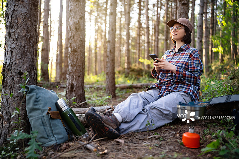 女人在露营旅行中，在森林里放松地使用手机图片素材