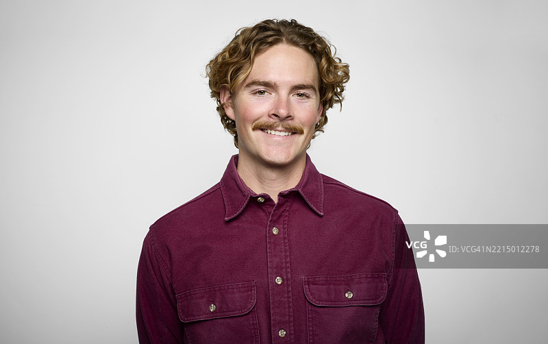 微笑男子的肖像，穿着休闲衬衫，背景为中性色调图片素材
