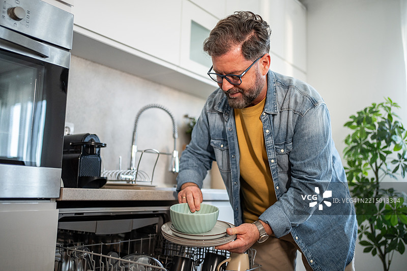 男子在现代厨房中清空洗碗机图片素材