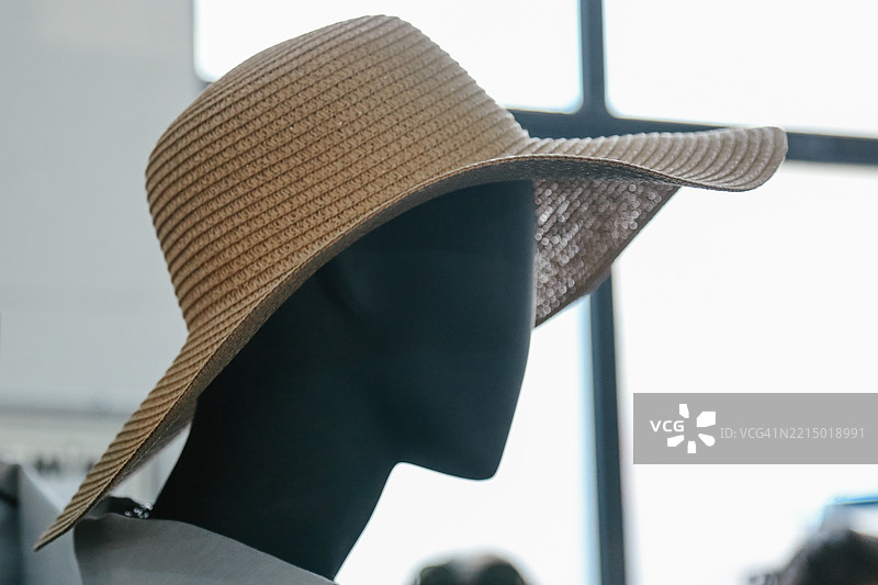 女性模特佩戴草帽，背景为模糊的购物中心图片素材