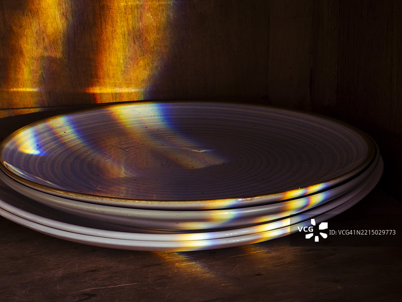 彩虹光在厨房的叠放盘子上创造出五彩斑斓的反射，正值黄金时刻。图片素材